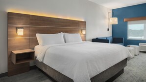 A modern hotel room with a large bed, bedside tables, a desk, and a chair.