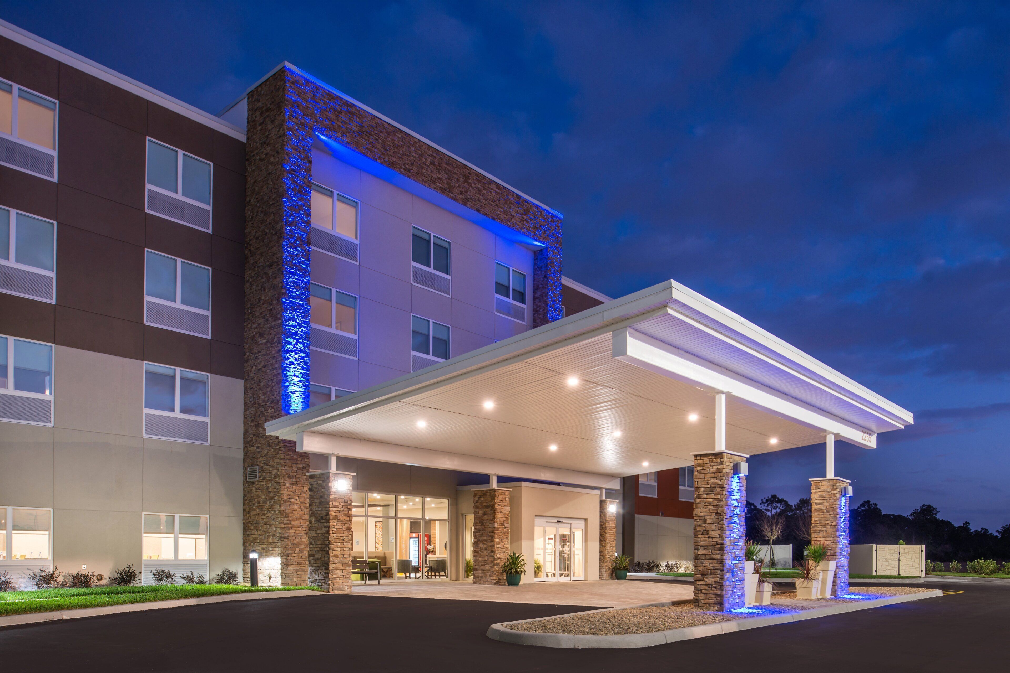 A hotel with a covered entrance, stone facade, and multiple windows.
