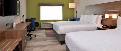 A hotel room with two beds, a desk, a chair, a television, and a window with blinds.