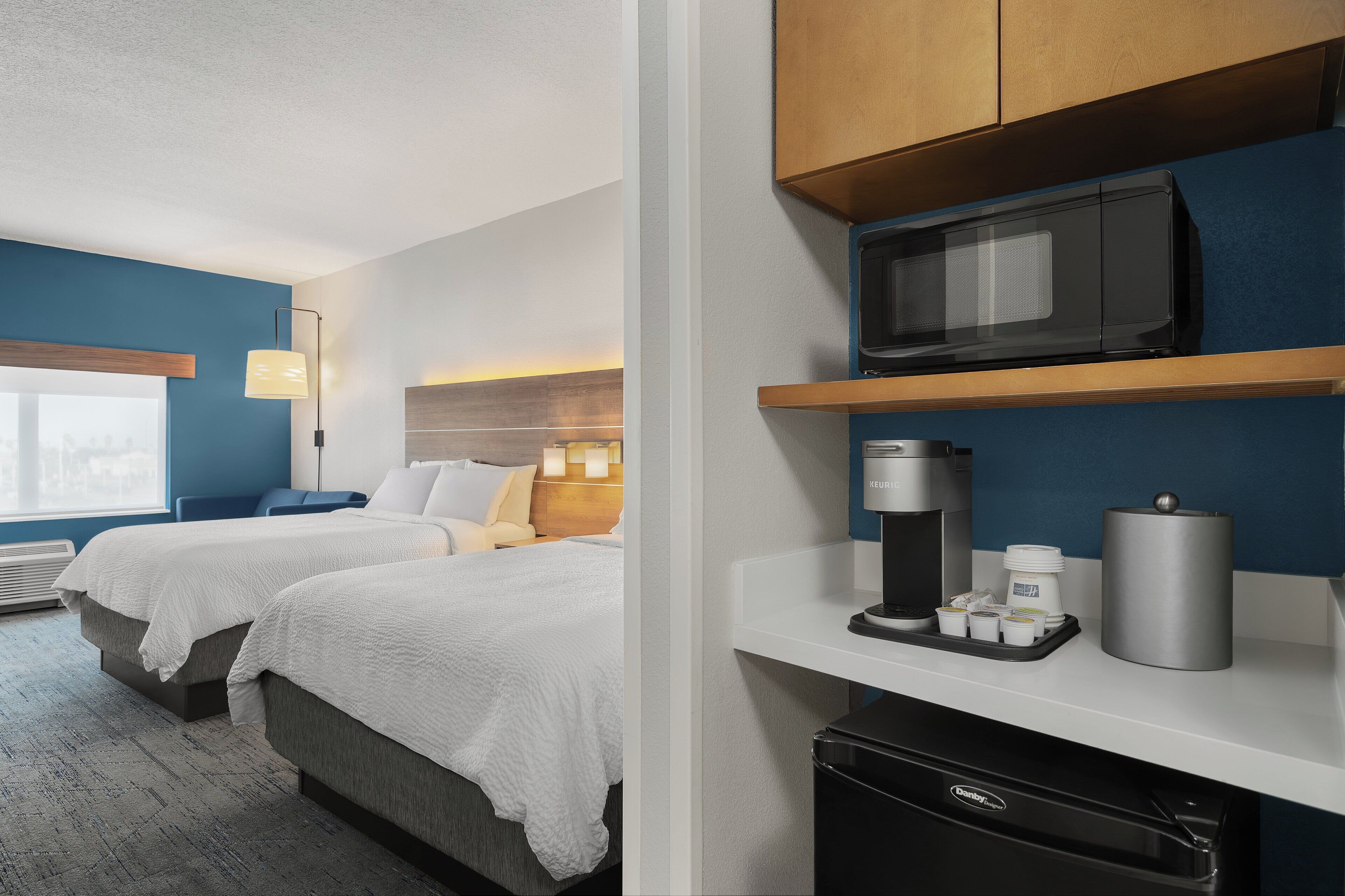 Habitación de hotel con dos camas, un minibar, un microondas y una cafetera.