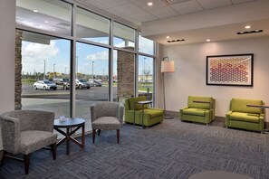 A hotel lobby with a seating area, a coffee table, and a lamp. - Holiday Inn Express & Suites West Melbourne by IHG (Melbourne)
