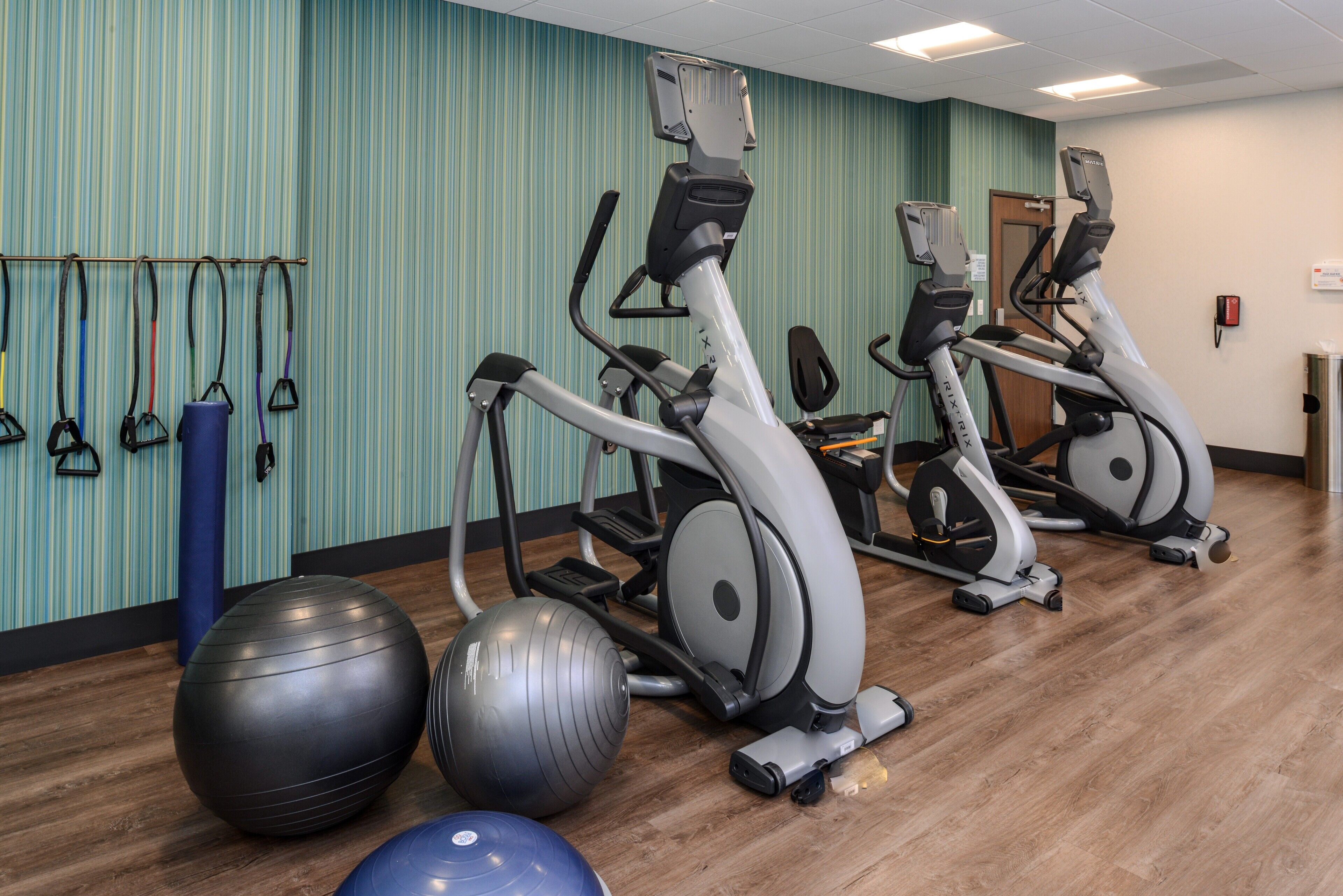 A gym with exercise equipment, including treadmills and stationary bikes, and exercise balls.