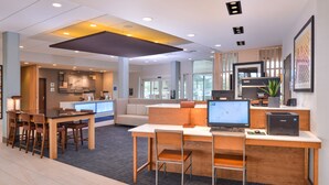 A modern office space with a reception desk, a seating area with a sofa, and a computer setup with a printer.