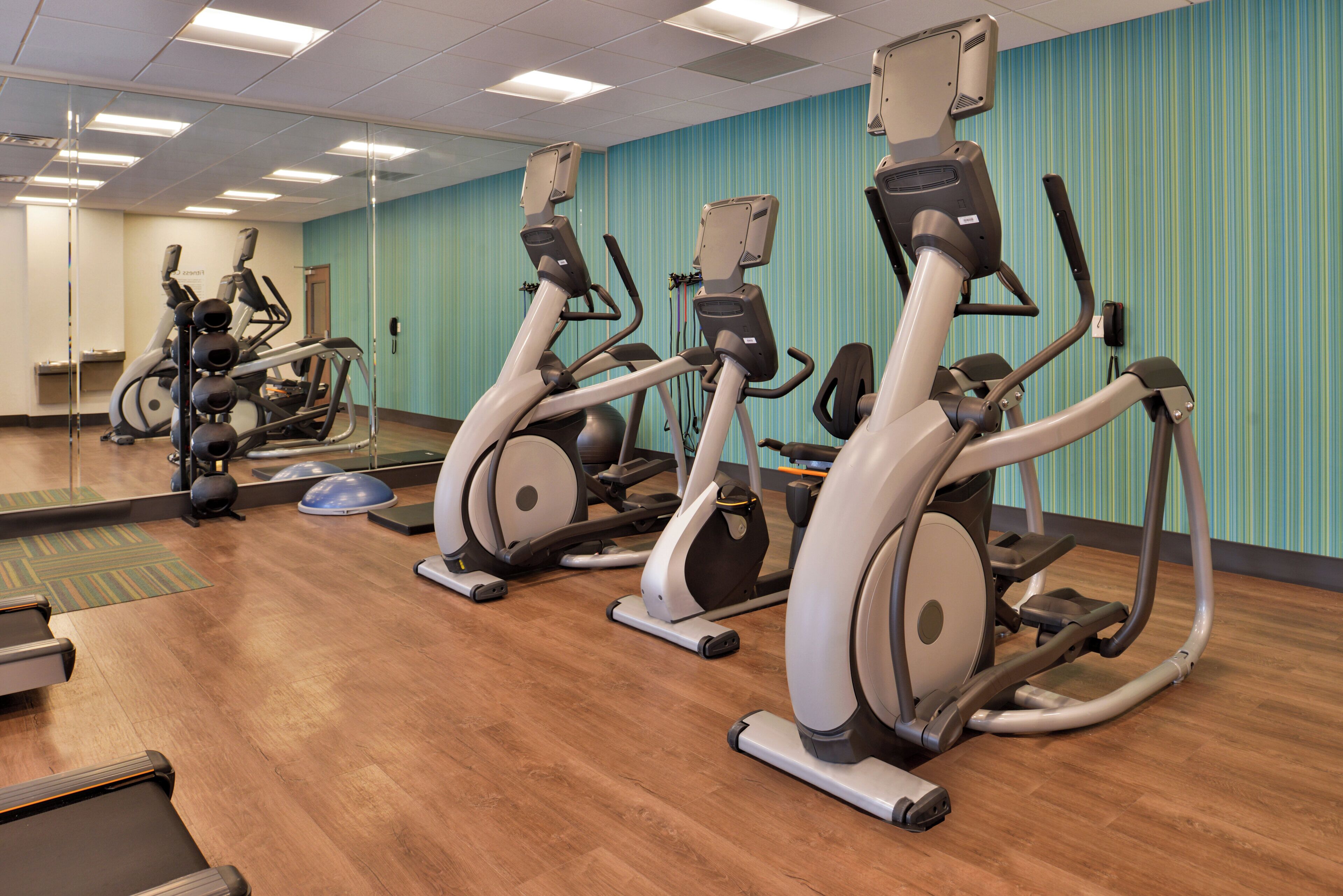 A gym with multiple stationary bikes and a mirrored wall.