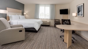 A hotel room with a bed, a desk, a chair, a TV, and a window with curtains. - Candlewood Suites Miami Intl Airport - 36th St by IHG (Miami)
