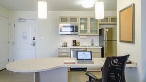 A modern kitchen with a central island, a microwave, a refrigerator, and a laptop on the island. - Candlewood Suites Miami Intl Airport - 36th St by IHG (Miami)