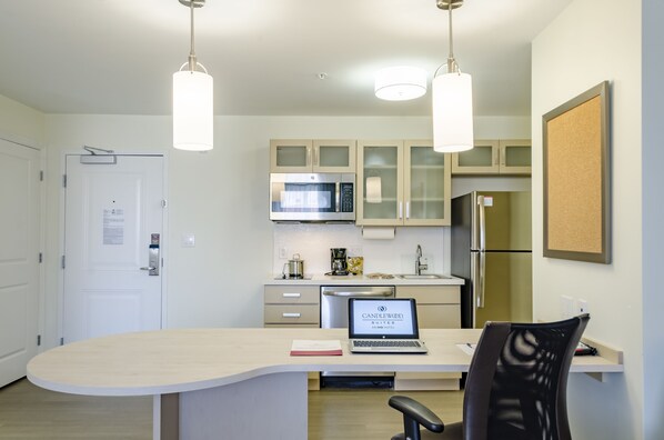 A modern kitchen with a central island, a microwave, a refrigerator, and a laptop on the island. - Candlewood Suites Miami Intl Airport - 36th St by IHG (Miami)