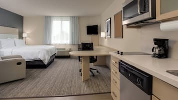 A hotel room with a bed, a desk, a chair, a television, a coffee maker, and a microwave.