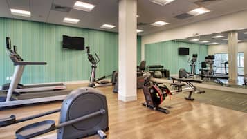 A gym with cardio equipment, weight machines, and a mirrored wall.