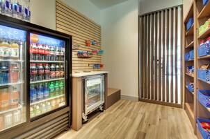 Un refrigerador para bebidas repleto de diversas opciones, una pequeña vitrina expositora y un separador de listones de madera.