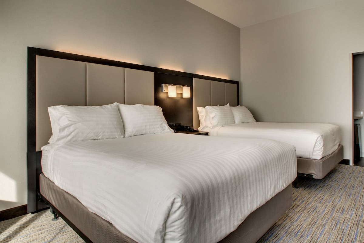 A hotel room with a large bed, two bedside tables, and a headboard with integrated lighting.