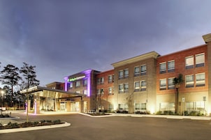 Edificio de Holiday Inn Express & Suites con entrada despejada, zona de estacionamiento y fachada bien iluminada.