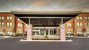 A modern building with a covered entrance, multiple windows, and a landscaped area with palm trees. - Holiday Inn Express & Suites Summerville by IHG (Summerville)