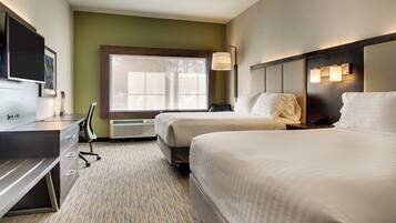 A hotel room with two beds, a desk, a chair, and a television.