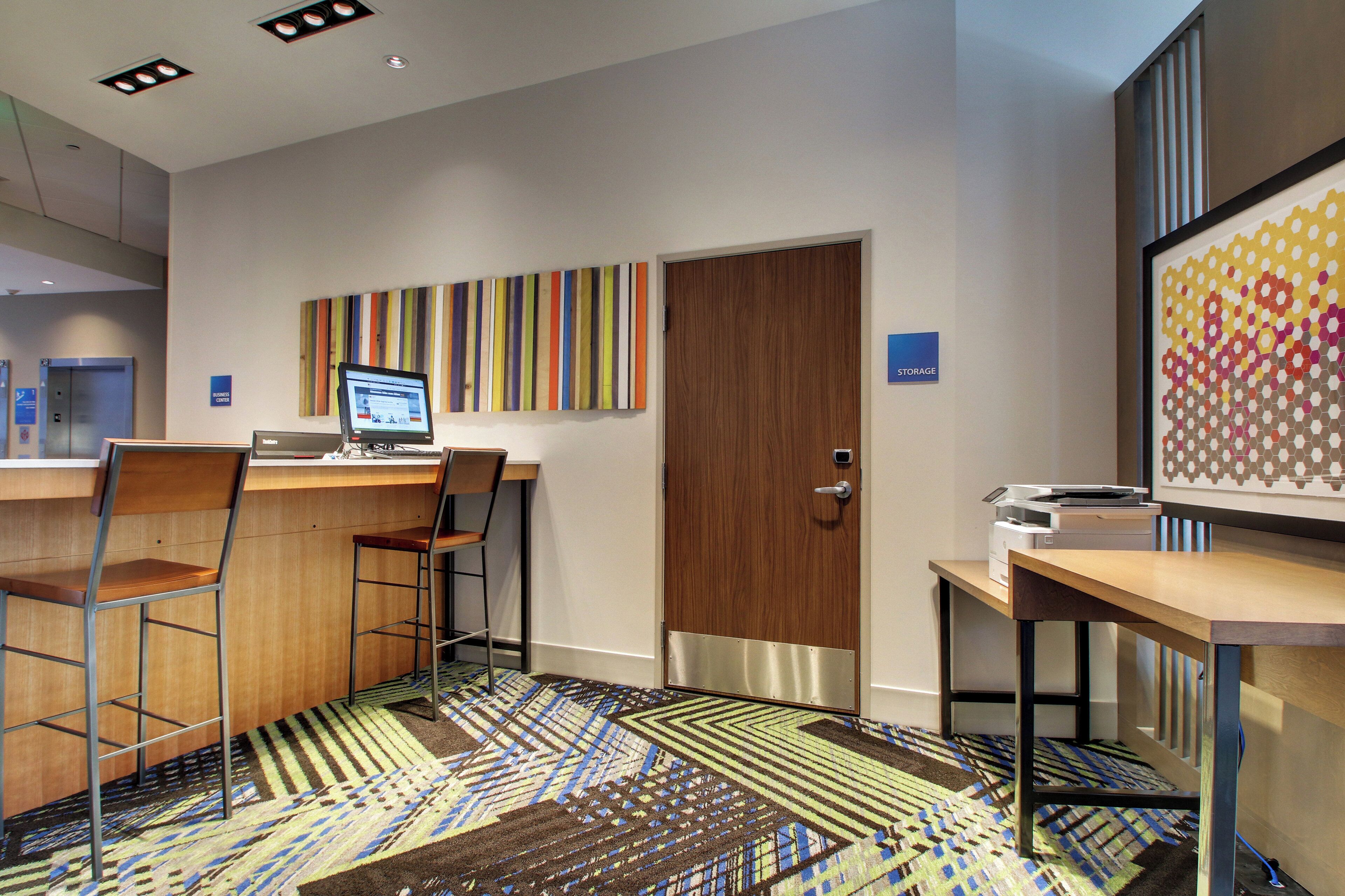 A modern office space with a desk, chairs, a computer, and a patterned carpet.