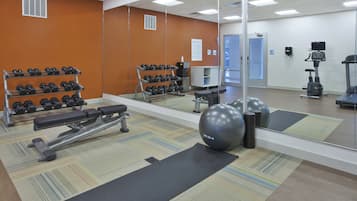Un gimnasio con equipamiento de ejercicio, un espejo y un cartel en la pared.