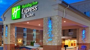 A Holiday Inn Express & Suites hotel with a brick facade, large windows, and a well-lit entrance. - Holiday Inn Express Auburn Hills South by IHG (Auburn Hills)