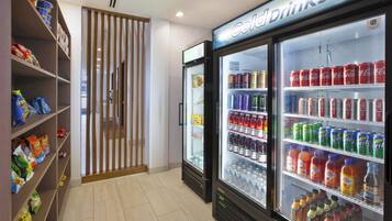 A refrigerated drink display with various beverages, a snack shelf with bags, and a wooden partition.