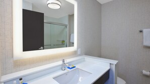 Une salle de bain avec un lavabo blanc, un miroir et des toilettes.