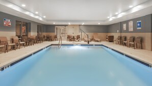 A swimming pool with chairs and tables, a lifeguard sign, and a door. - Holiday Inn Express Auburn Hills South by IHG (Auburn Hills)