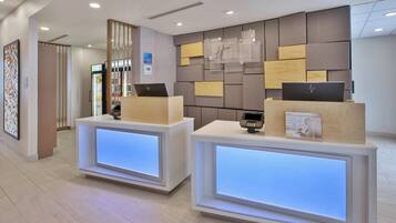 A reception area with two reception desks, a wall-mounted sign, and a framed picture on the left.