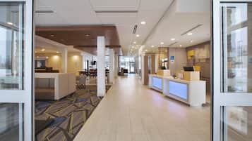 Un vestíbulo de hotel con mostrador de recepción, zona de estar y suelo alfombrado.