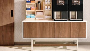 Une cuisine moderne avec des meubles en bois, un coin café équipé d’une machine à café et des boîtes de rangement.