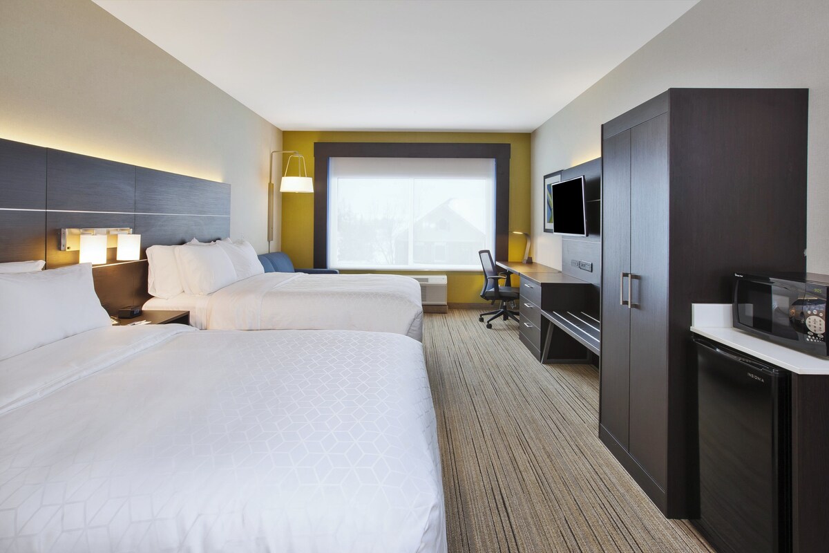 A hotel room with two beds, a desk, a TV, and a wardrobe.
