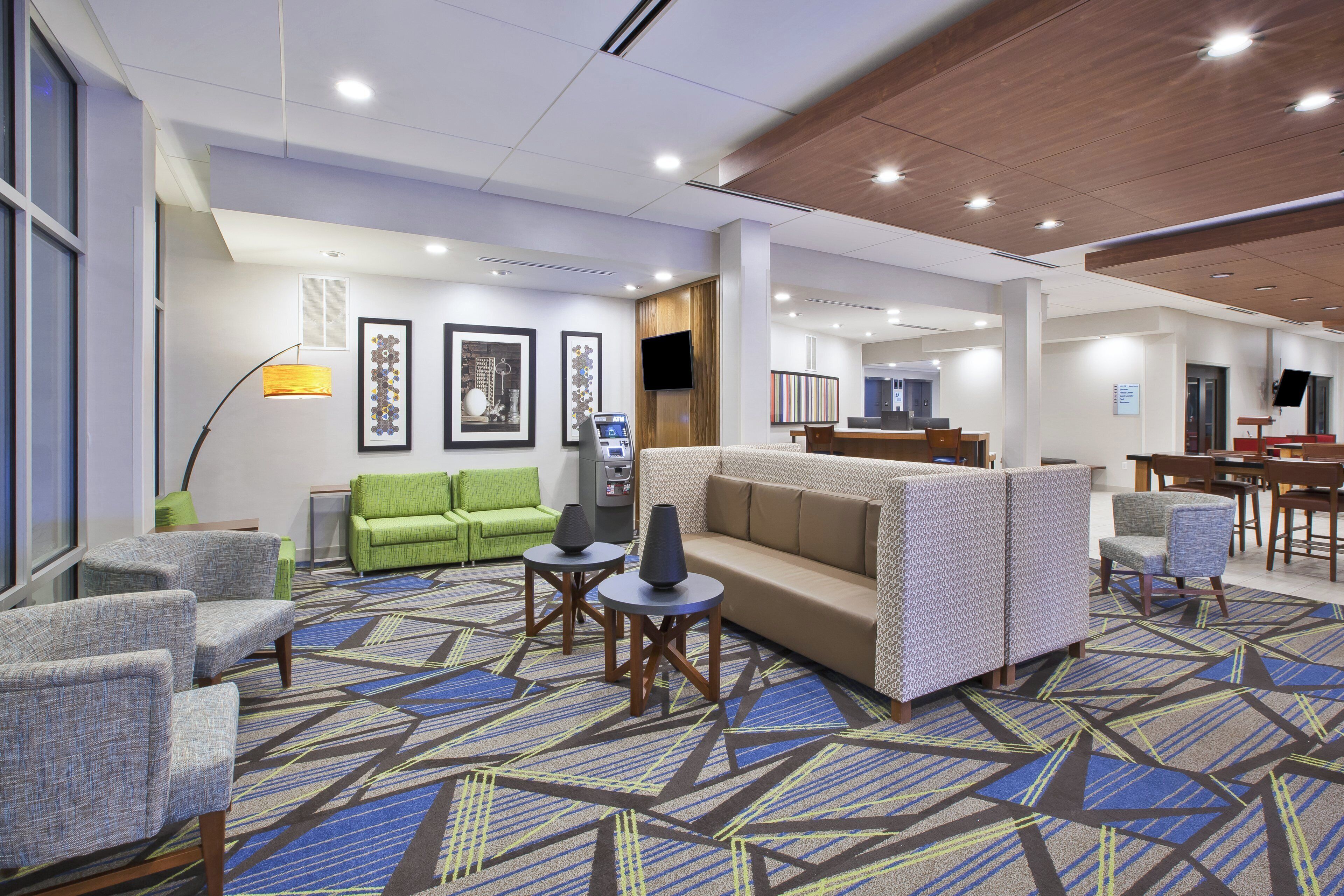 A hotel lobby with seating areas, a reception desk, and a flat-screen TV.