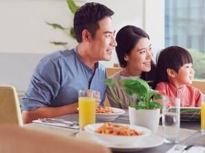 A family dining at a table with plates of food, glasses of juice, and a potted plant. - Holiday Inn Kunshan Huaqiao by IHG (Suzhou)