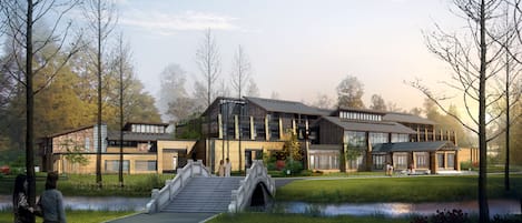 Un bâtiment moderne avec une façade en pierre, de grandes fenêtres et un pont menant à l’entrée.