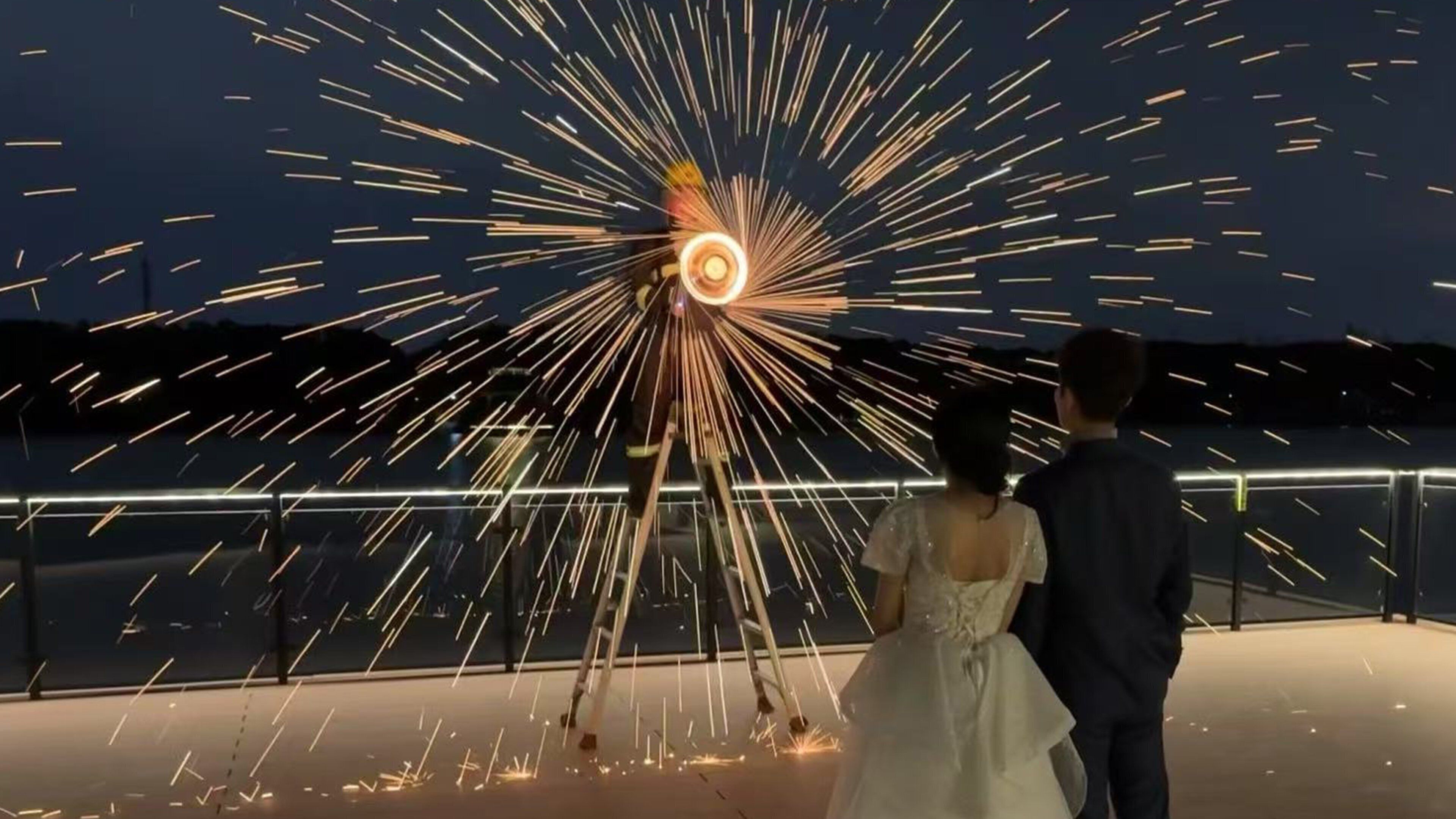 Un couple se tient sur un balcon, avec un jeu de lumière en arrière-plan.