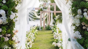 A wedding arch with white flowers and greenery, a grassy aisle, and a wooden structure in the background. - Holiday Inn Kunshan Huaqiao by IHG (Suzhou)