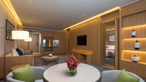 A modern hotel room with a round table, two armchairs, a TV, and wooden paneling. - Holiday Inn Kunshan Huaqiao by IHG (Suzhou)