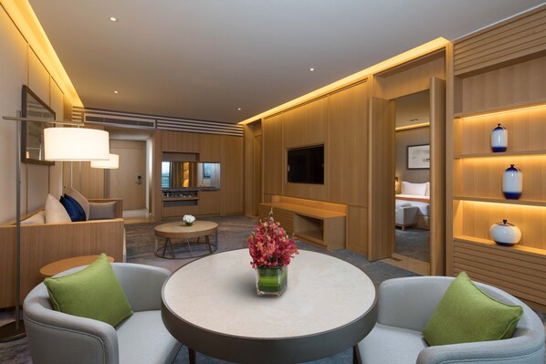 A modern hotel room with a round table, two armchairs, a TV, and wooden paneling. - Holiday Inn Kunshan Huaqiao by IHG (Suzhou)
