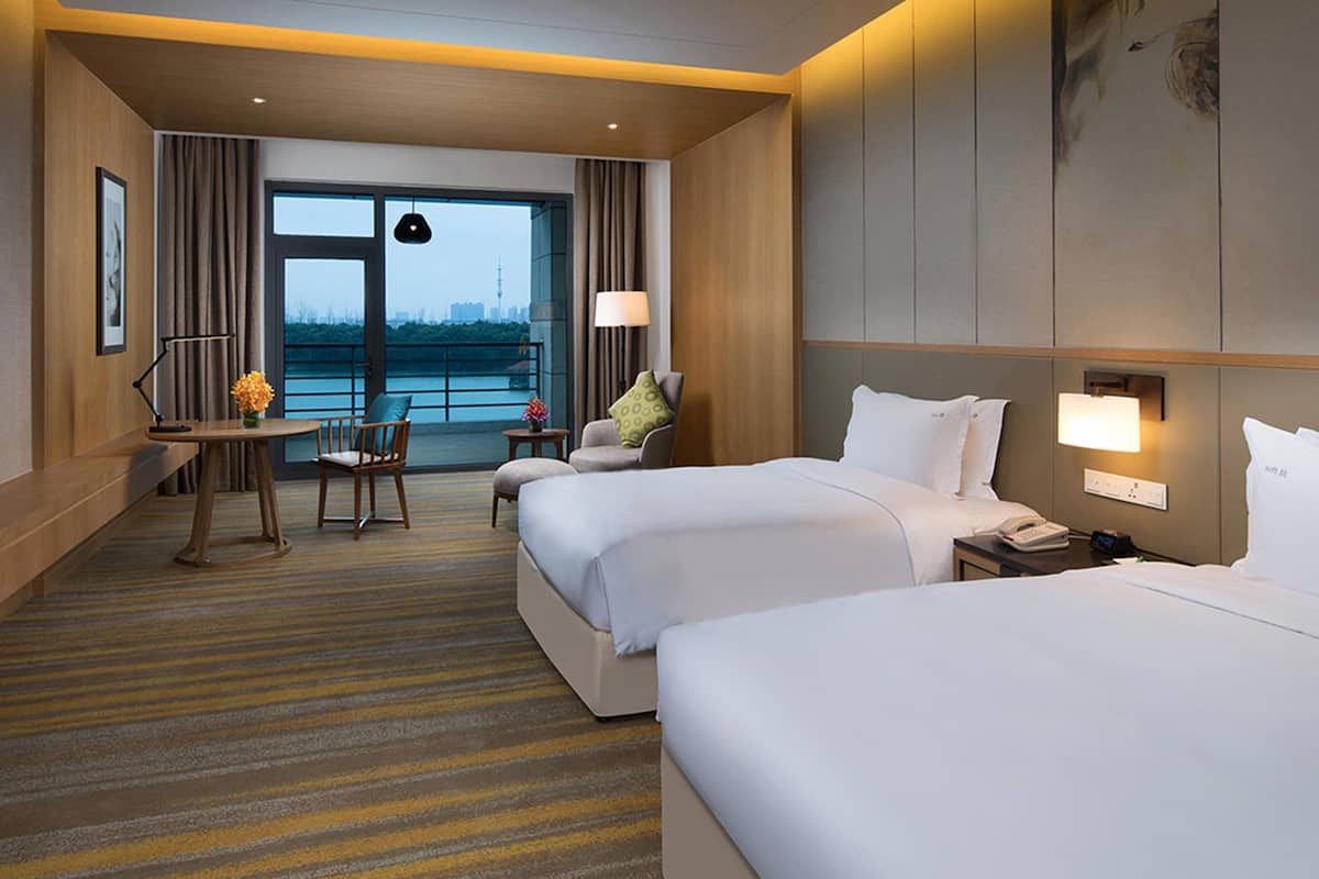 Habitación de hotel con dos camas, un escritorio, una silla y vistas a un cuerpo de agua.