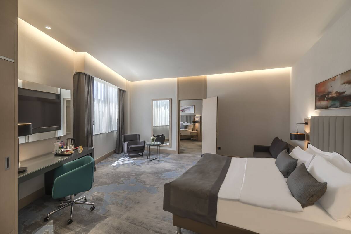 Une chambre d’hôtel moderne équipée d’un grand lit, d’un bureau, d’une chaise et d’un téléviseur.