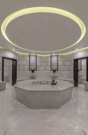 Uma área de recepção moderna e circular, com piso de mármore, um balcão central e um design de teto singular.