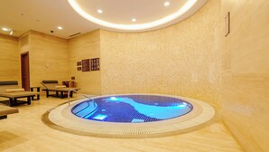 Een wellnessruimte met een whirlpool, zitplaatsen en een informatiemuur.