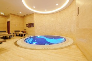 Een wellnessruimte met een whirlpool, zitplaatsen en een informatiemuur.