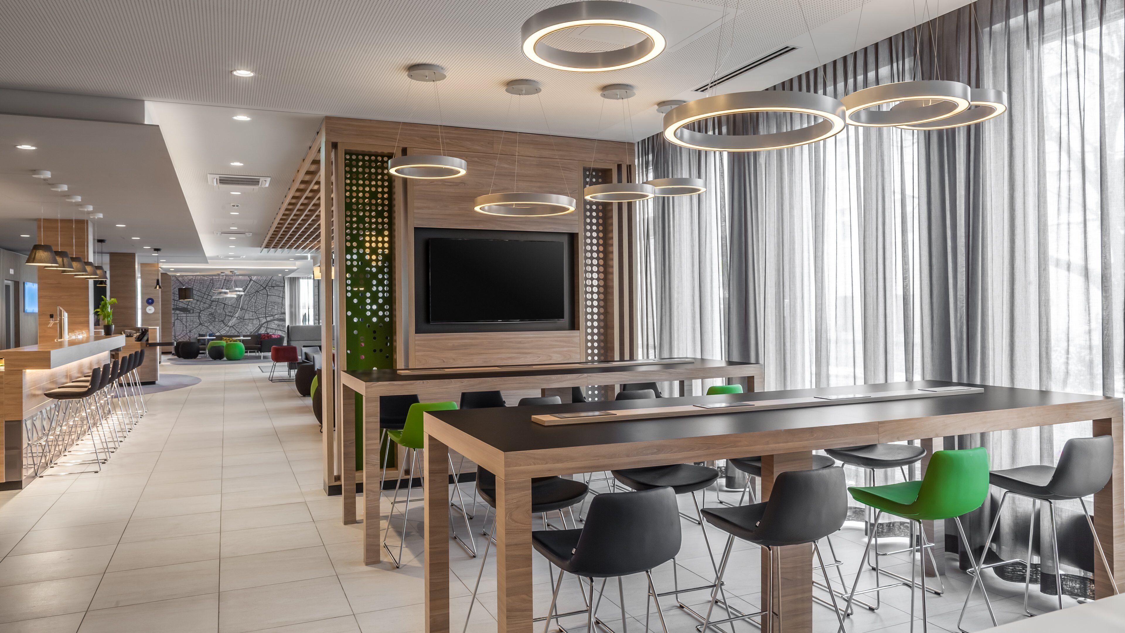 Un interior moderno con una larga mesa de comedor, varias sillas, una zona de bar y un televisor de pantalla plana grande.