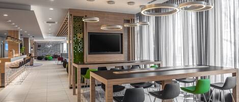Un interior moderno con una larga mesa de comedor, varias sillas, una zona de bar y un televisor de pantalla plana grande.