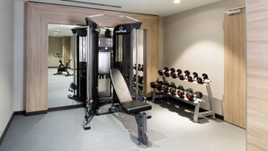 A gym with a Smith machine, dumbbells, and a mirror. - Holiday Inn Express Munich - City East by IHG (Munich)