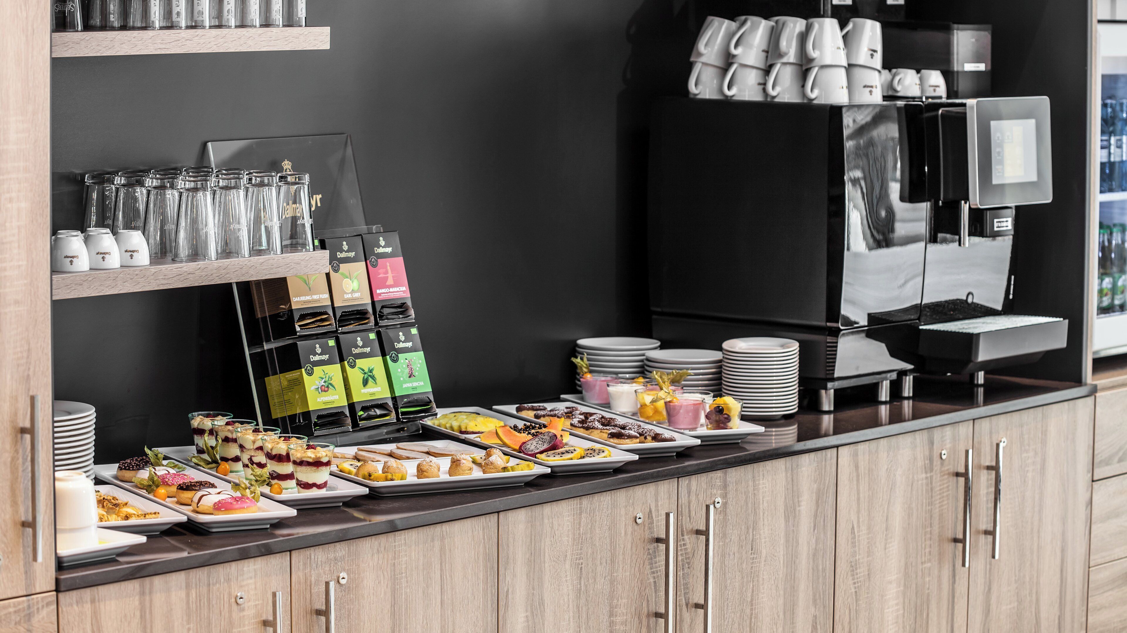 A buffet setup with various food items, a coffee machine, and a beverage dispenser.