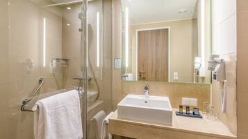 A modern bathroom with a glass shower enclosure, a white sink, and a hairdryer mounted on the wall.