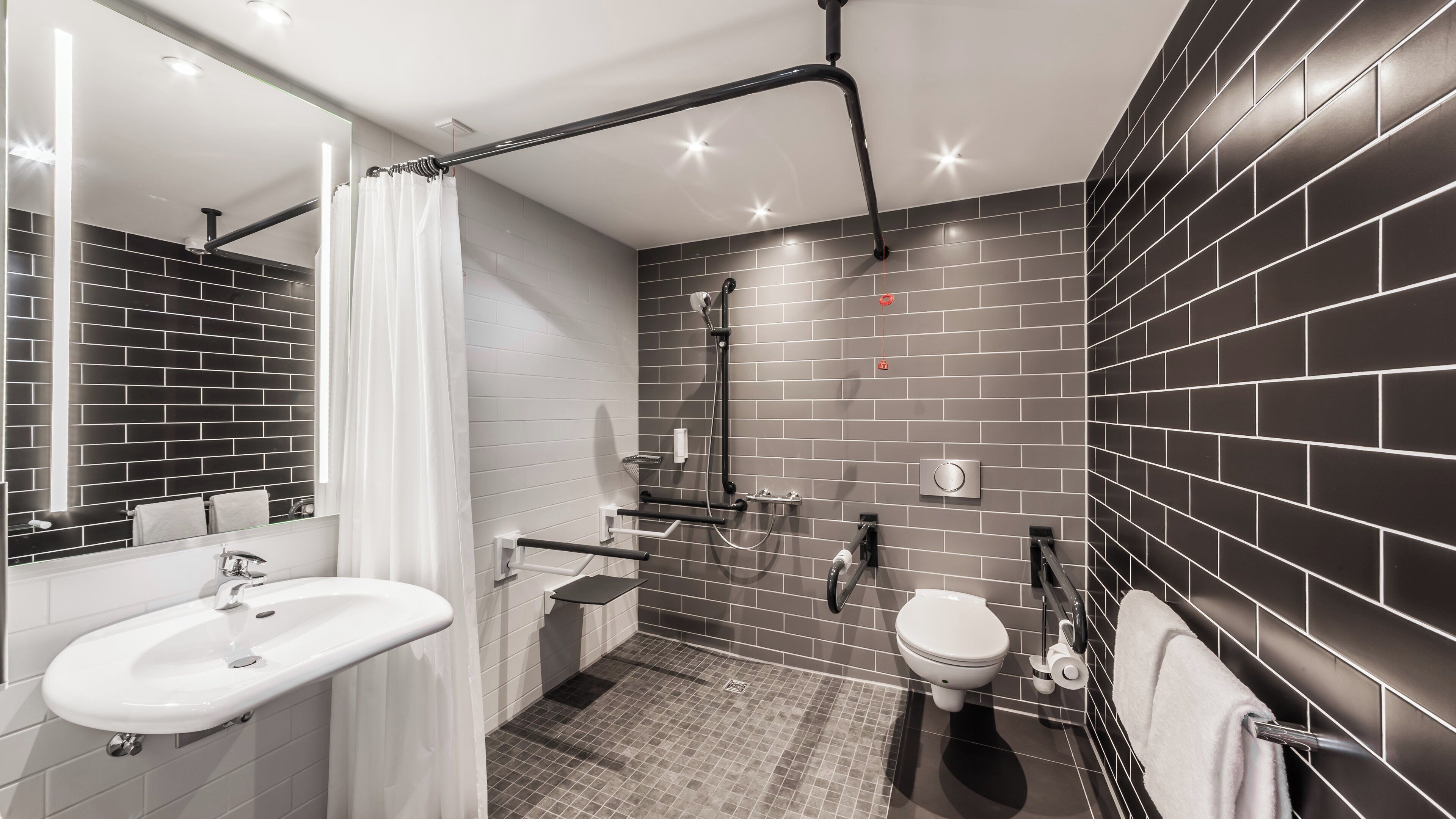 A modern bathroom with a white sink, a toilet, and a shower area.
