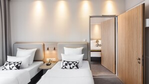 A hotel room with two beds, a bedside table with a phone, and a wardrobe. - Holiday Inn Express Munich - City East by IHG (Munich)