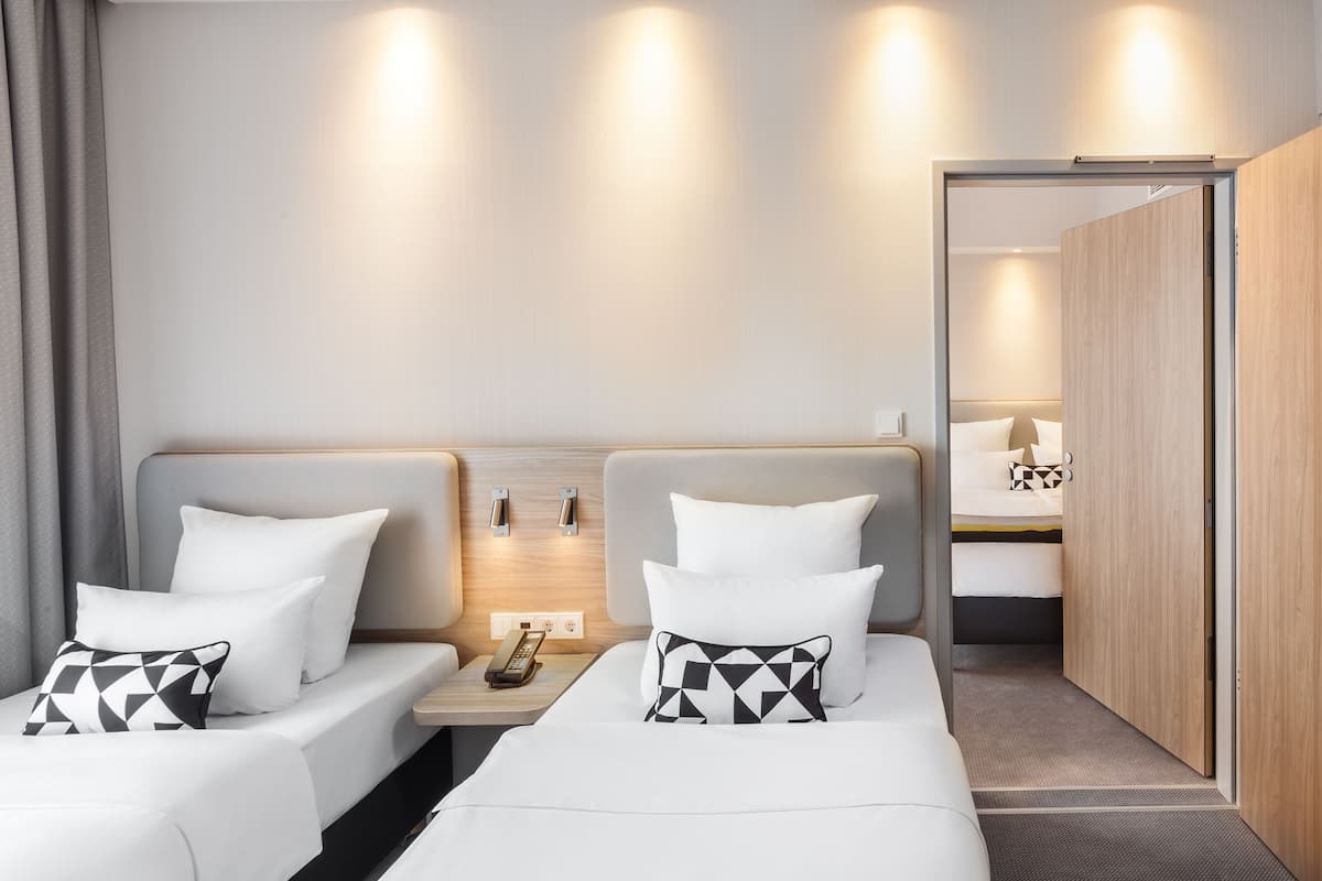 Une chambre d’hôtel avec deux lits, une table de chevet avec un téléphone et une armoire.