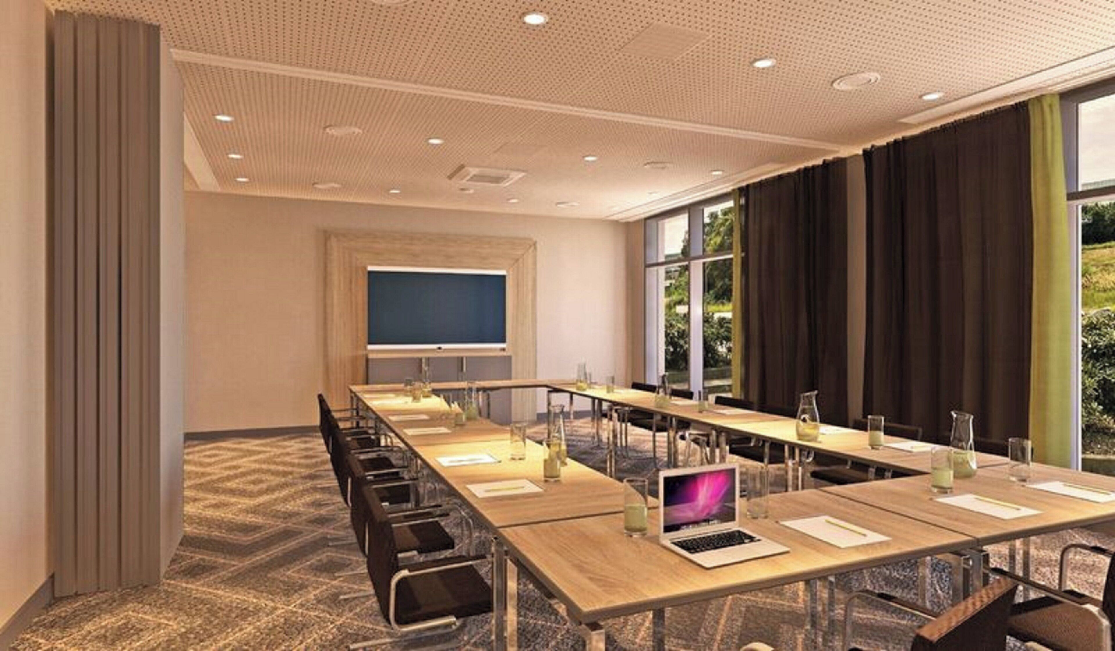 Une salle de conférence équipée d’une longue table, de chaises, d’un écran de projection et d’un ordinateur portable.