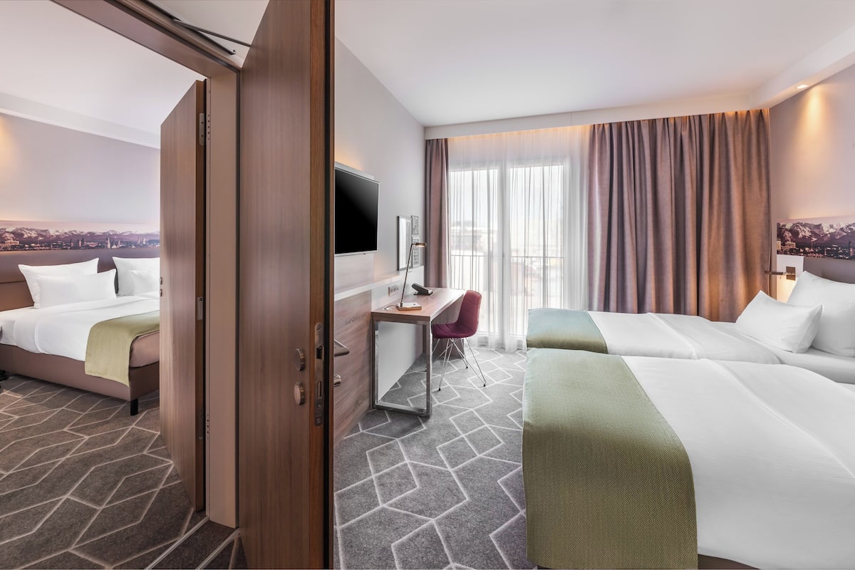 Une chambre d’hôtel avec deux lits, un bureau, une télévision et une vue sur la ville.